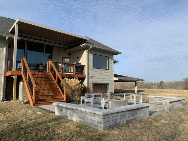 A patio with a fire pit and benches in the back yard.
