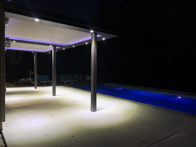 A pool area with lights and a pergola.