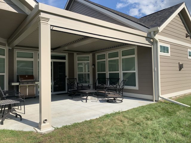 A patio with chairs and tables under an awning.