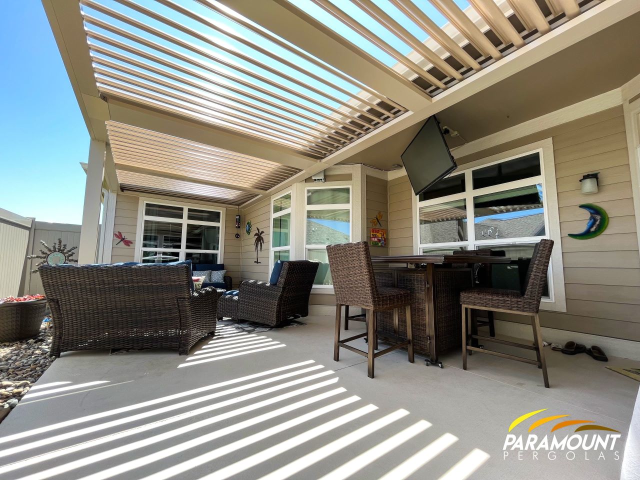 A covered patio with a tv and wicker furniture.